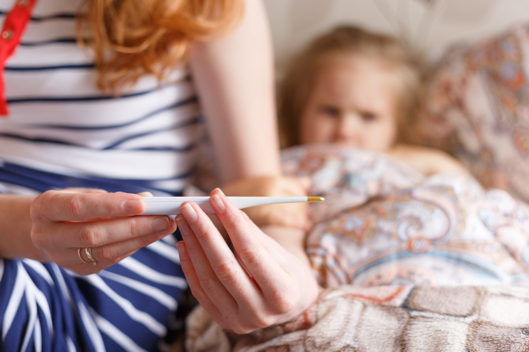 madre mirando termómetro de niña enferma en invierno