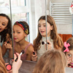 maquillaje niña mientras se mira en el espejo.